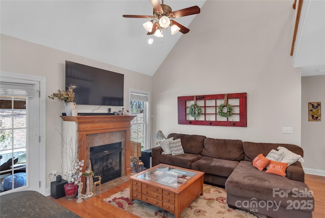 living room featuring ceiling fan, a fireplace, light hardwood / wood-style flooring, and high vaulted ceiling