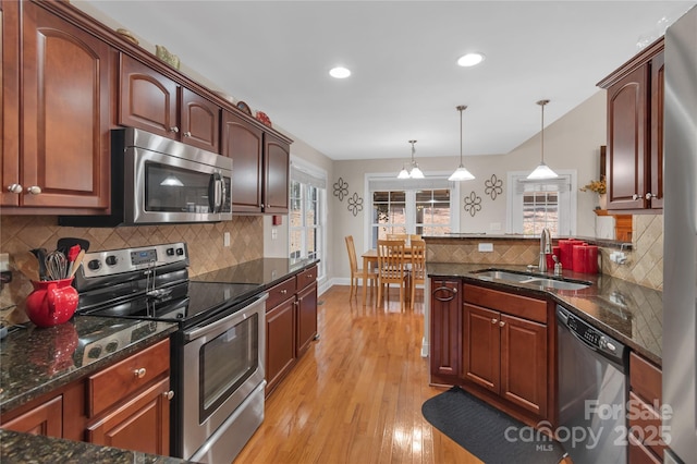 kitchen featuring decorative light fixtures, light hardwood / wood-style floors, decorative backsplash, sink, and stainless steel appliances