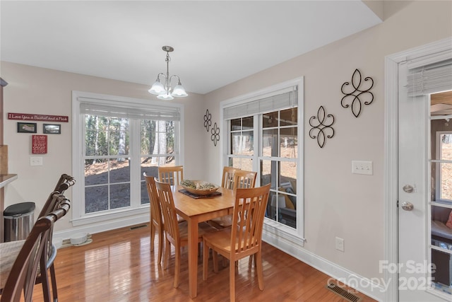 dining space featuring hardwood / wood-style flooring and a notable chandelier