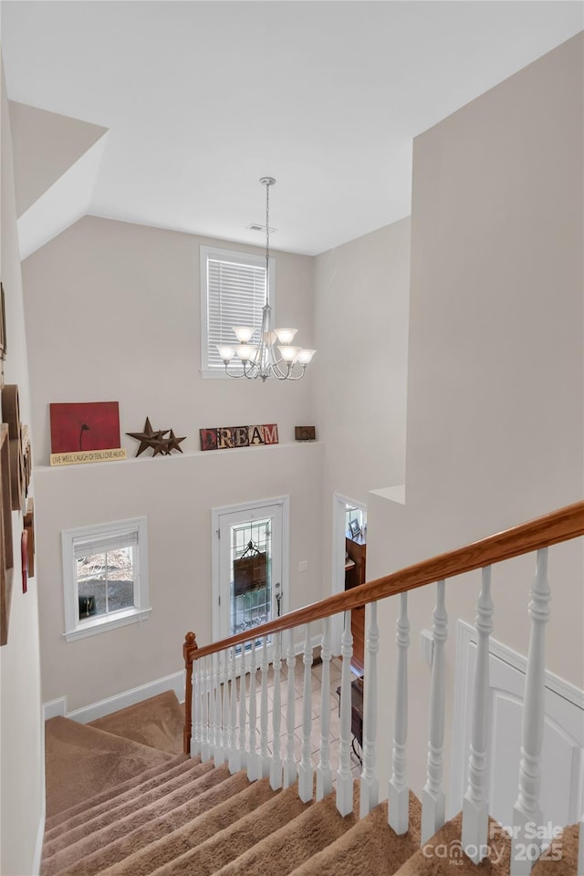 stairway with lofted ceiling, an inviting chandelier, and carpet flooring