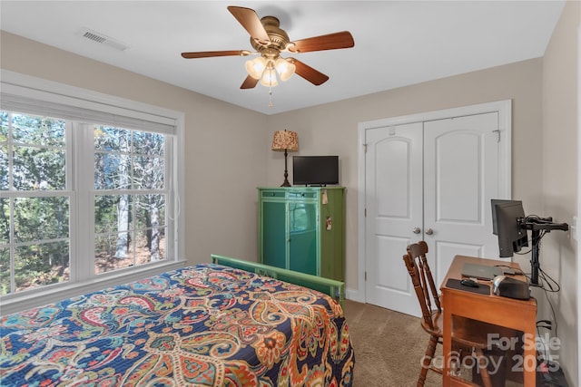 carpeted bedroom featuring ceiling fan and a closet