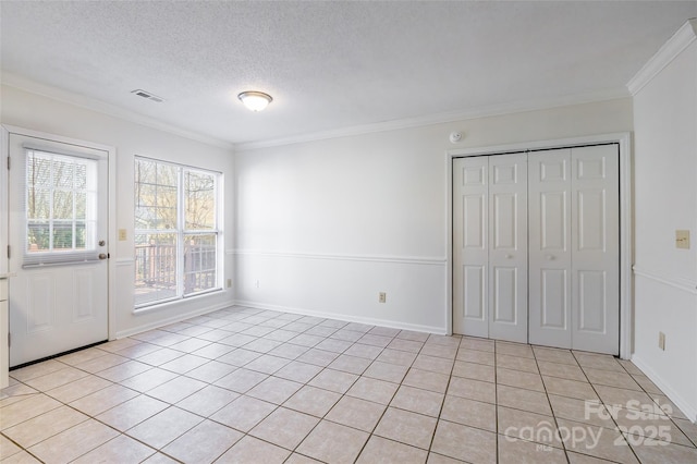 tiled spare room with crown molding and a textured ceiling