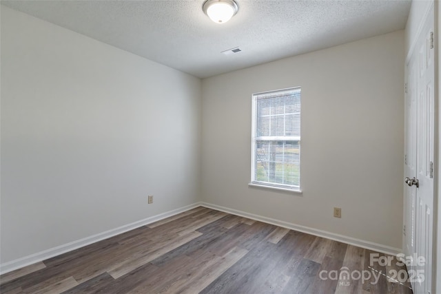 unfurnished room with wood-type flooring, plenty of natural light, and a textured ceiling