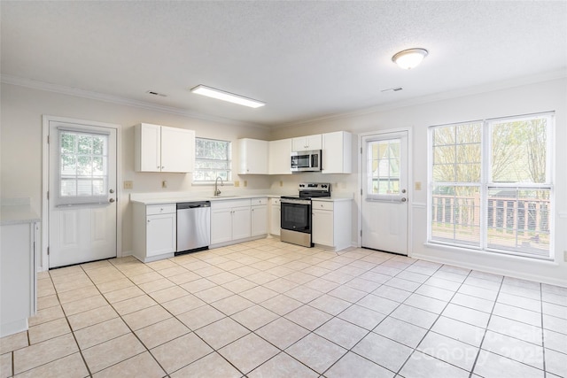 kitchen with crown molding, appliances with stainless steel finishes, light tile patterned floors, and white cabinets