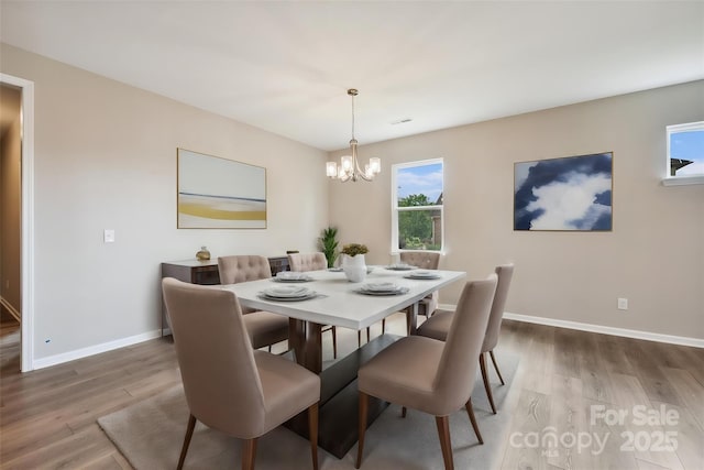 dining space with hardwood / wood-style flooring and a chandelier