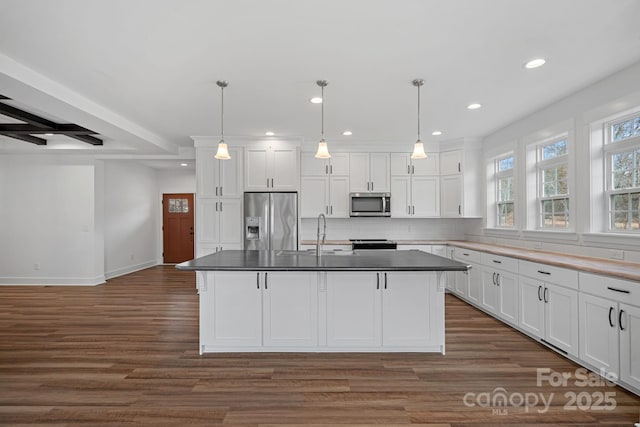 kitchen with decorative light fixtures, a kitchen island, white cabinets, and appliances with stainless steel finishes