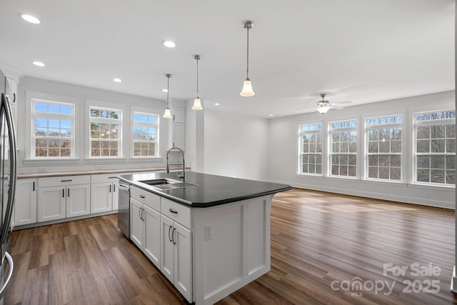 kitchen featuring white cabinetry, sink, hanging light fixtures, a kitchen island with sink, and dark wood-type flooring