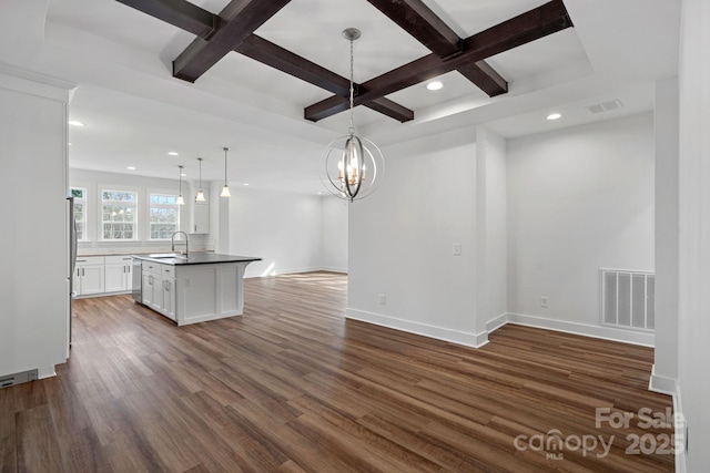 kitchen featuring white cabinetry, sink, hanging light fixtures, dark wood-type flooring, and a center island with sink