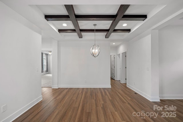 spare room with dark wood-type flooring, coffered ceiling, an inviting chandelier, and beam ceiling