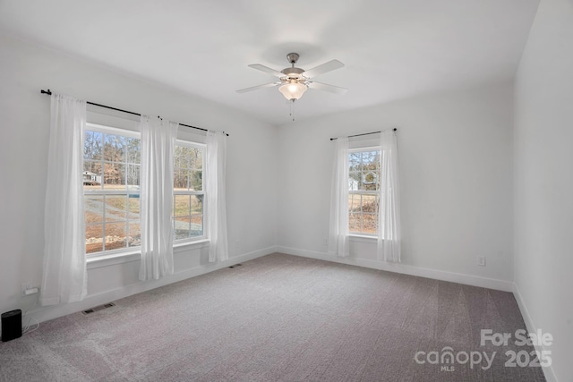 spare room with ceiling fan, plenty of natural light, and carpet floors