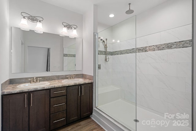 bathroom featuring hardwood / wood-style floors, vanity, and a tile shower