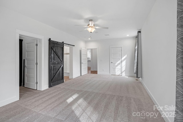 spare room with light carpet, a barn door, and ceiling fan