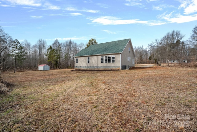 view of front of house with a storage shed, cooling unit, and a front lawn