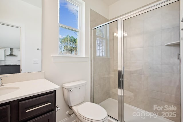 bathroom featuring toilet, a shower with door, and vanity