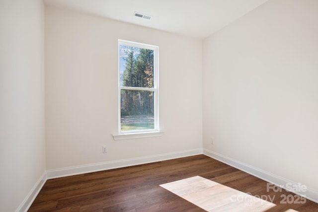 empty room featuring a wealth of natural light and dark hardwood / wood-style floors