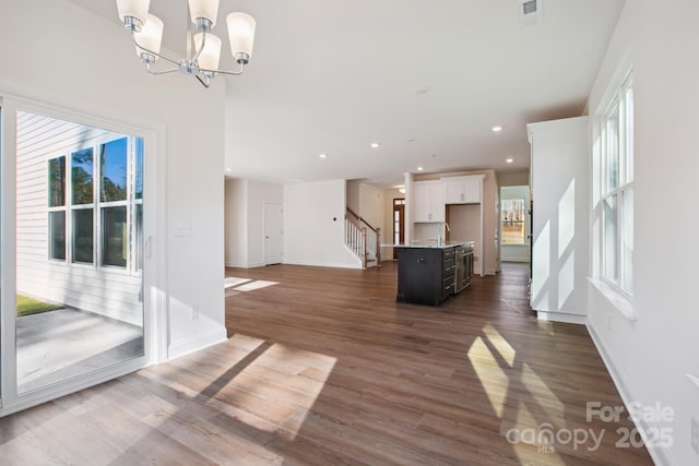 unfurnished living room with an inviting chandelier and dark hardwood / wood-style floors