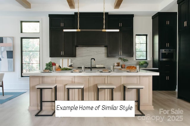 kitchen with sink, a kitchen island with sink, a breakfast bar area, and decorative backsplash