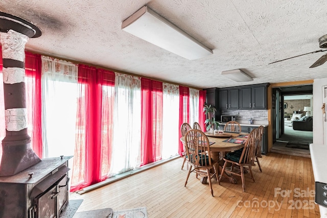 dining space with wood-type flooring, a textured ceiling, and ceiling fan