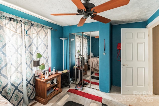 bedroom with ceiling fan, a textured ceiling, a closet, and light carpet