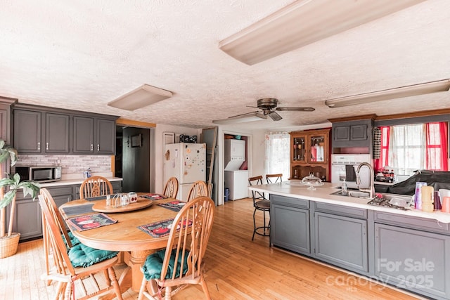 dining room featuring light hardwood / wood-style floors, sink, a textured ceiling, and ceiling fan