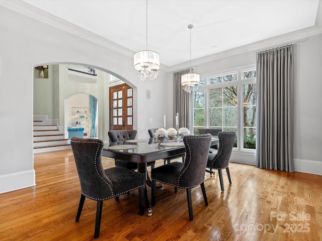 dining area with light hardwood / wood-style floors, crown molding, and a chandelier