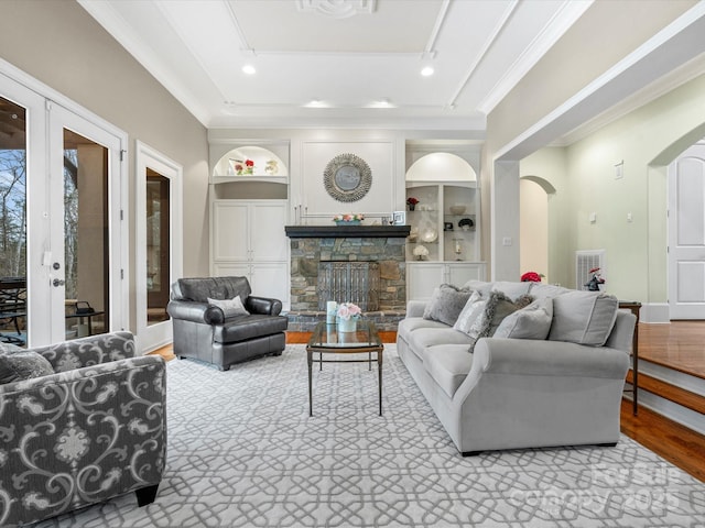 living room featuring french doors, light wood-type flooring, built in shelves, a fireplace, and rail lighting