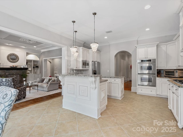 kitchen with pendant lighting, a center island, white cabinetry, stainless steel appliances, and light tile patterned flooring