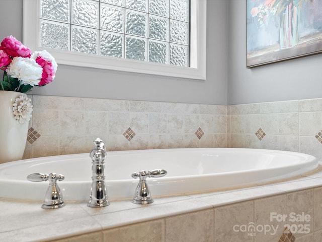 bathroom with a healthy amount of sunlight and a relaxing tiled tub