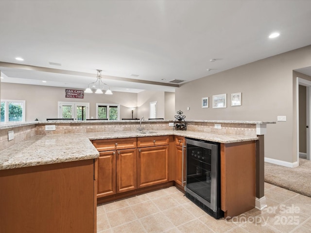 kitchen with sink, pendant lighting, light stone countertops, and beverage cooler