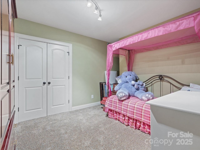 bedroom featuring a closet, rail lighting, and light carpet