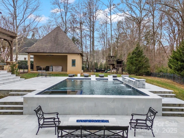 view of swimming pool with a patio area, a jacuzzi, a playground, an outdoor fire pit, and pool water feature