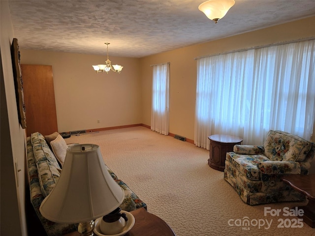 carpeted living room featuring a textured ceiling and an inviting chandelier