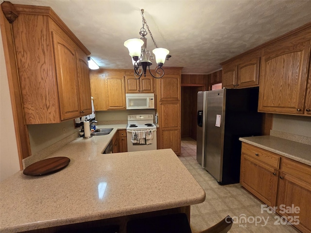 kitchen featuring decorative light fixtures, a notable chandelier, kitchen peninsula, sink, and white appliances