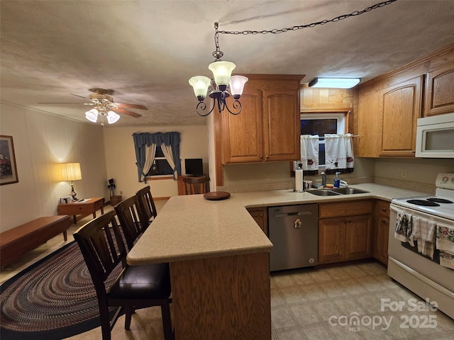 kitchen featuring pendant lighting, white appliances, sink, kitchen peninsula, and a breakfast bar