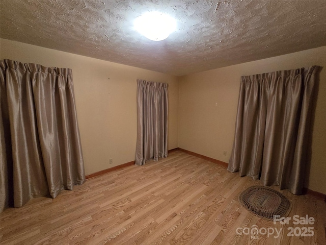 spare room with a textured ceiling and light wood-type flooring