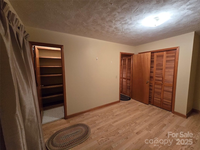 unfurnished bedroom with a closet, a textured ceiling, and light hardwood / wood-style flooring