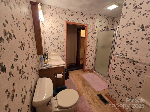 bathroom featuring an enclosed shower, vanity, wood-type flooring, and toilet