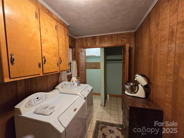 laundry room featuring cabinets, crown molding, washing machine and dryer, and wooden walls