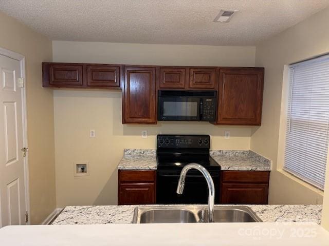 kitchen with light stone counters, sink, a textured ceiling, and black appliances