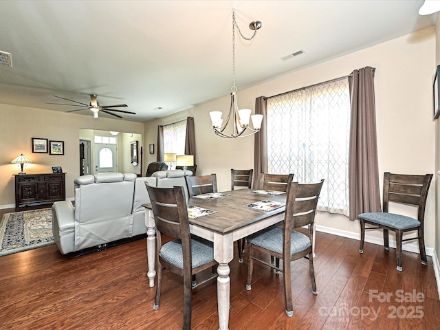 dining area with ceiling fan with notable chandelier and dark wood-type flooring