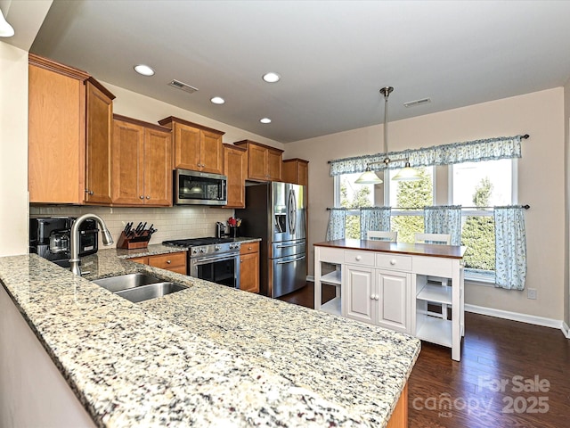 kitchen with pendant lighting, sink, appliances with stainless steel finishes, backsplash, and kitchen peninsula