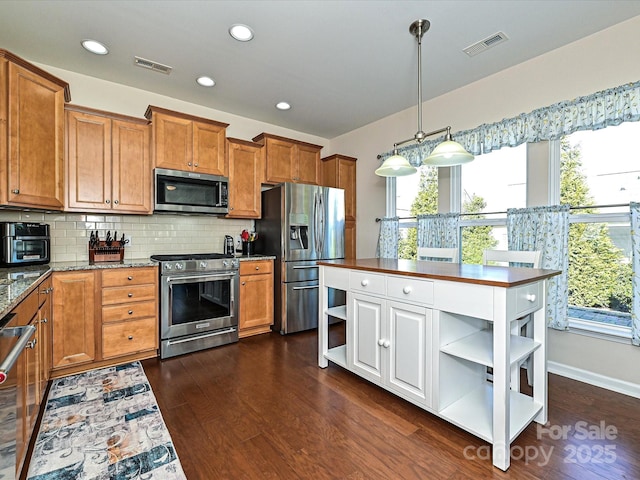 kitchen featuring dark wood-type flooring, light stone counters, decorative light fixtures, stainless steel appliances, and decorative backsplash