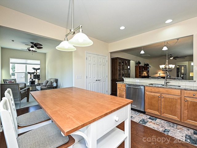 kitchen with pendant lighting, sink, a kitchen breakfast bar, light stone countertops, and stainless steel dishwasher