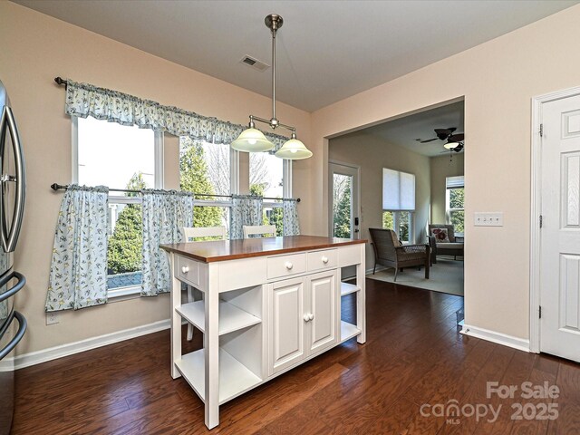 dining area with dark wood-style flooring, visible vents, and baseboards