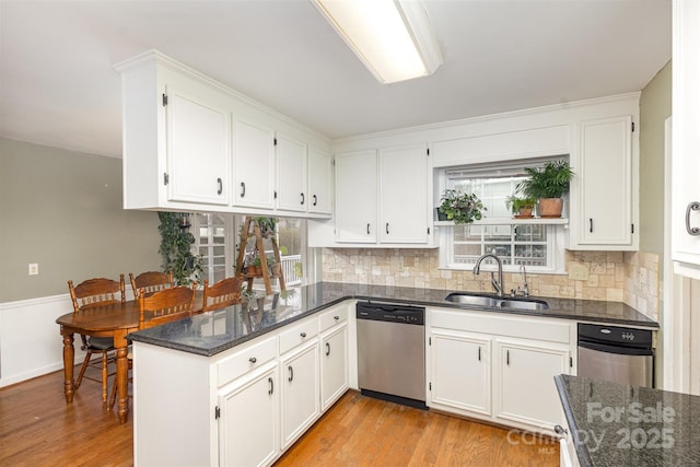 kitchen featuring dishwasher, white cabinetry, dark stone countertops, sink, and light wood-type flooring