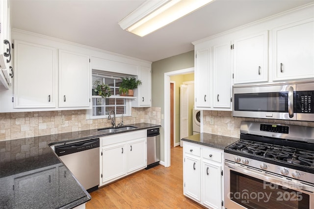 kitchen featuring appliances with stainless steel finishes, dark stone countertops, a sink, and white cabinets