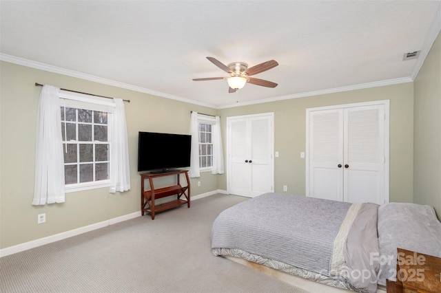 carpeted bedroom featuring crown molding, multiple closets, visible vents, a ceiling fan, and baseboards