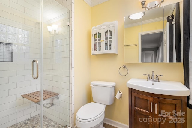 full bathroom featuring baseboards, toilet, crown molding, vanity, and a shower stall