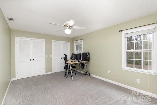 office featuring carpet floors, a ceiling fan, visible vents, and baseboards