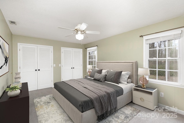 bedroom with light carpet, multiple windows, visible vents, and multiple closets